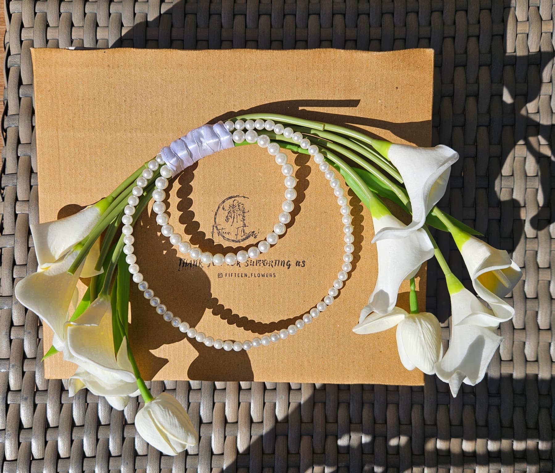 White lily and tulip purse bouquet resting on cream satin