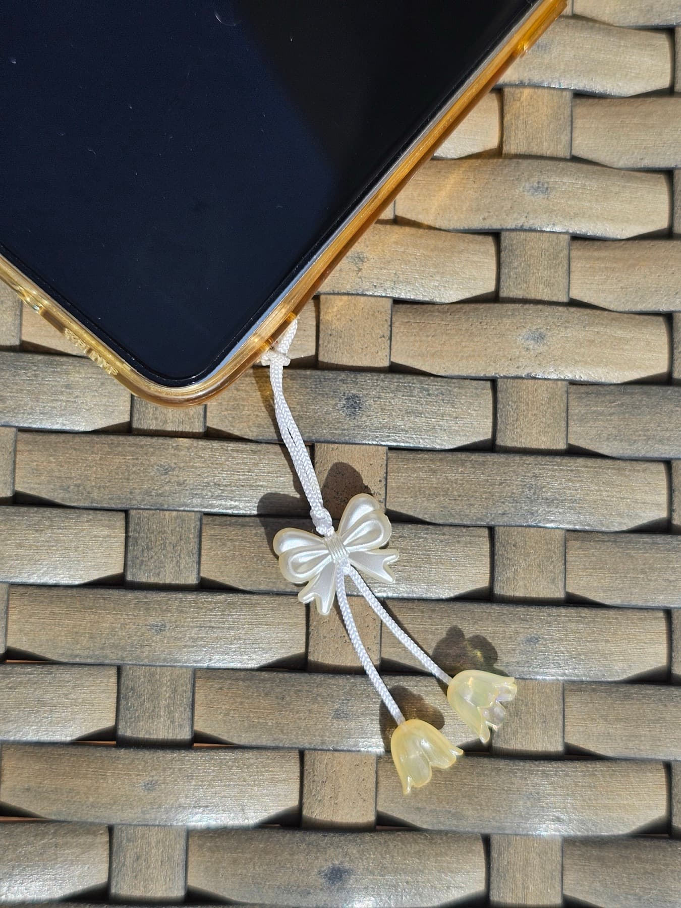 Tiny pearl bow charm tied to a woven bag