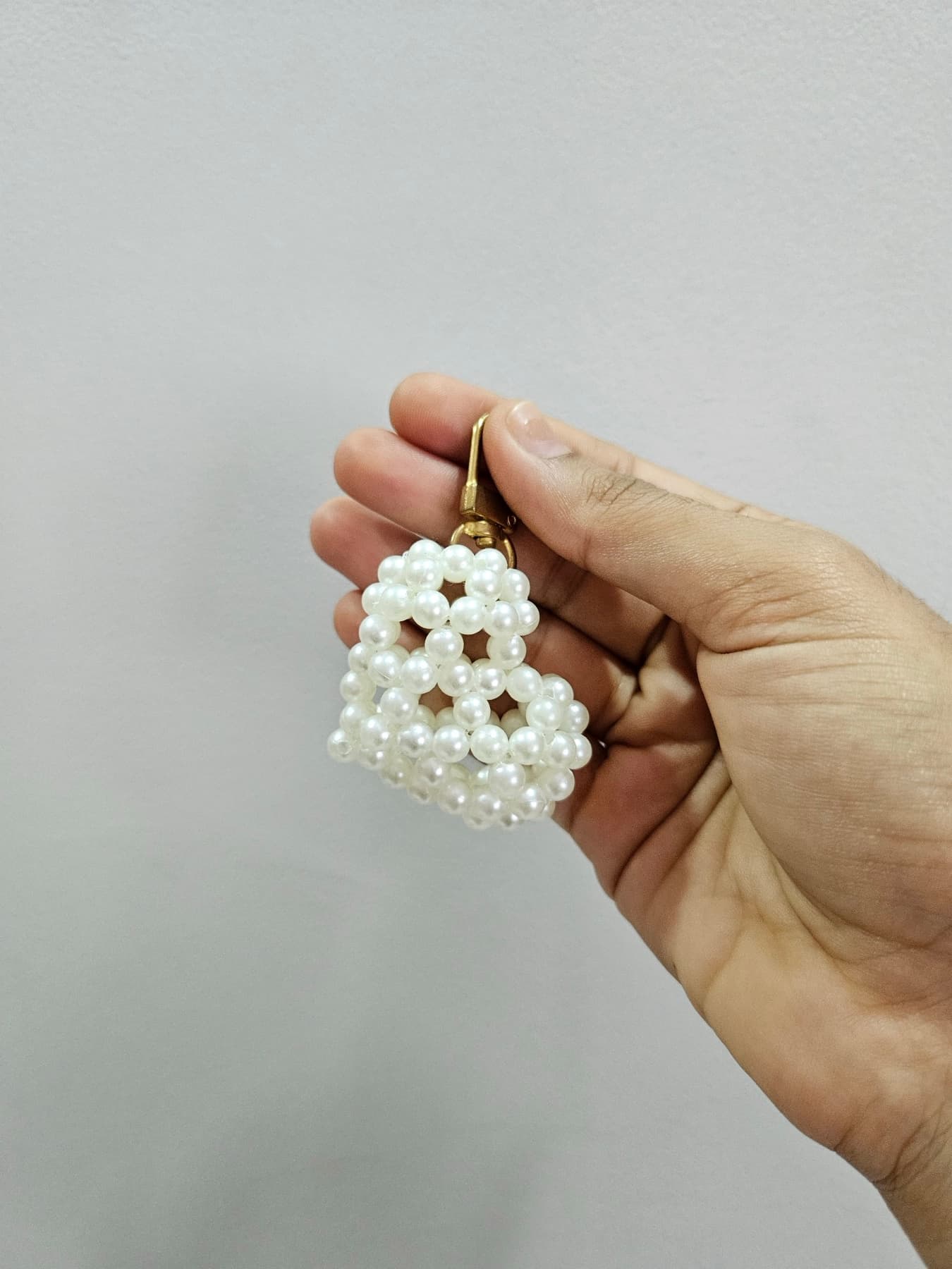 Small beaded pearl heart charm held in a hand