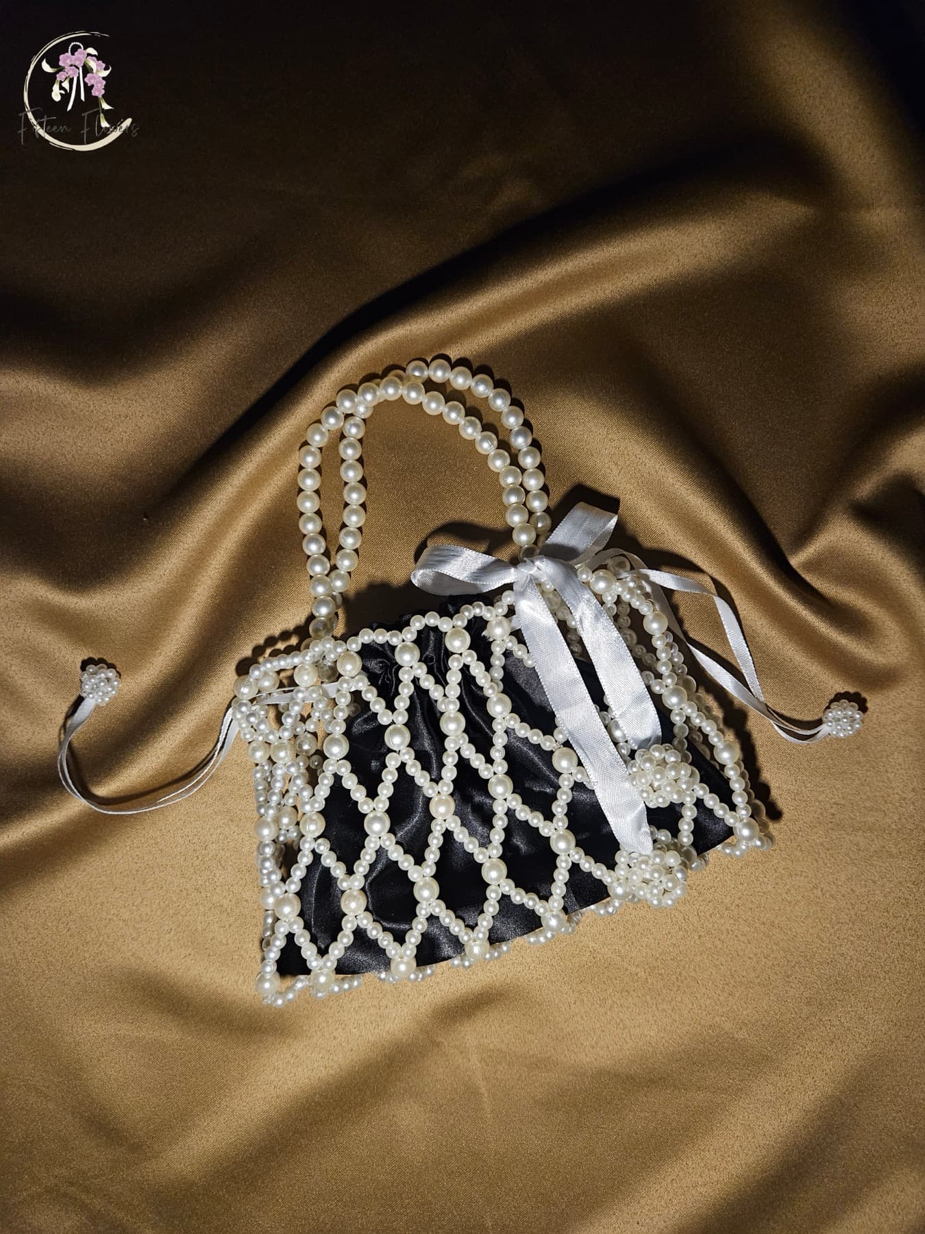 Open-weave pearl bag finished with a ribbon bow charm