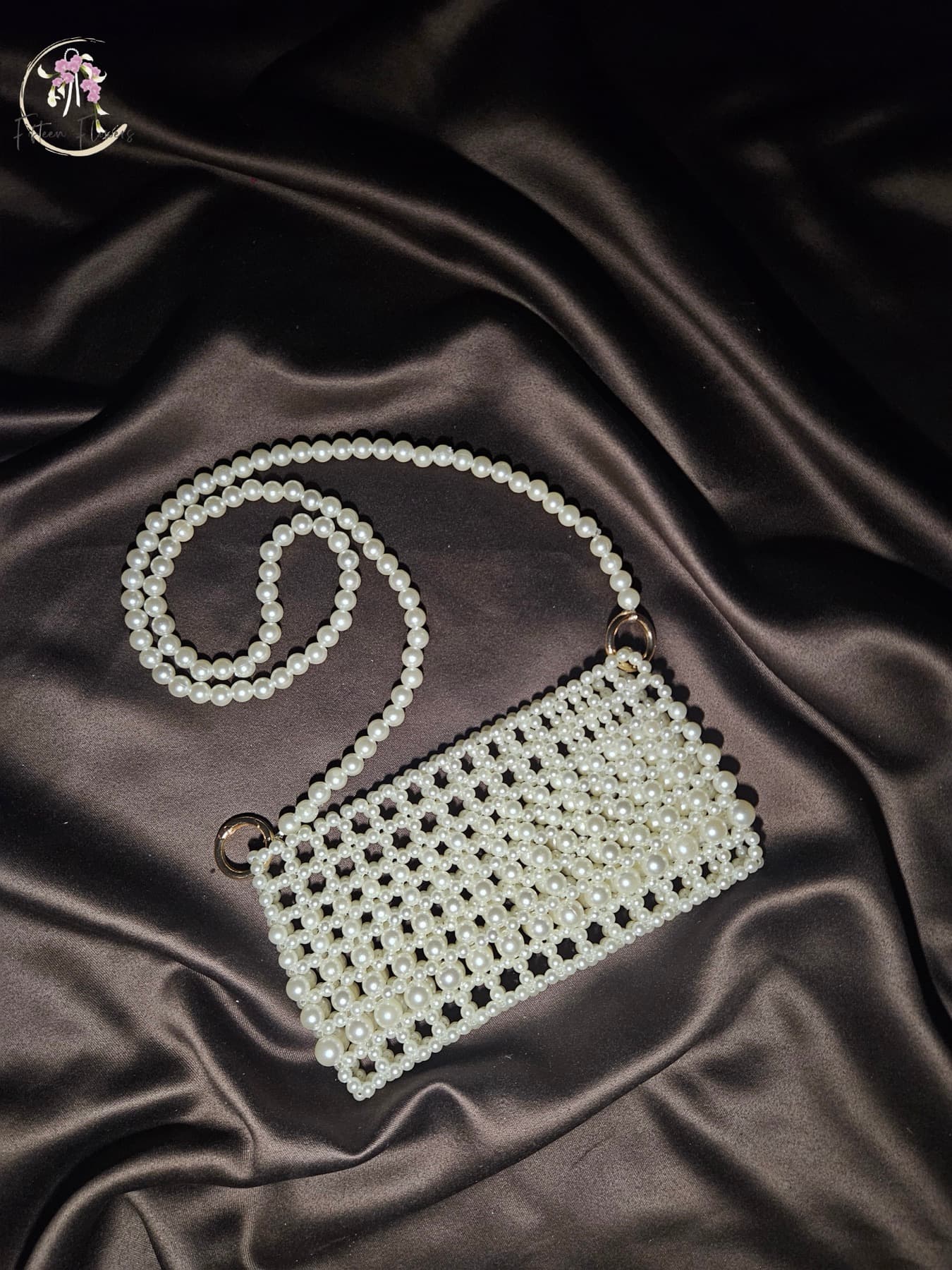 Woven pearl shoulder bag with long pearl strap on dark satin